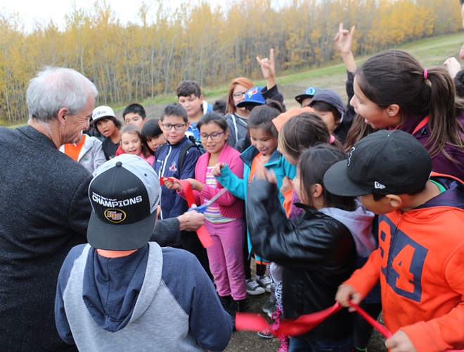 Bike Park organizer Don Patterson cuts the ribbon on September 30, opening the Enoch Bike Park as Kitaskinaw students cheer him on.