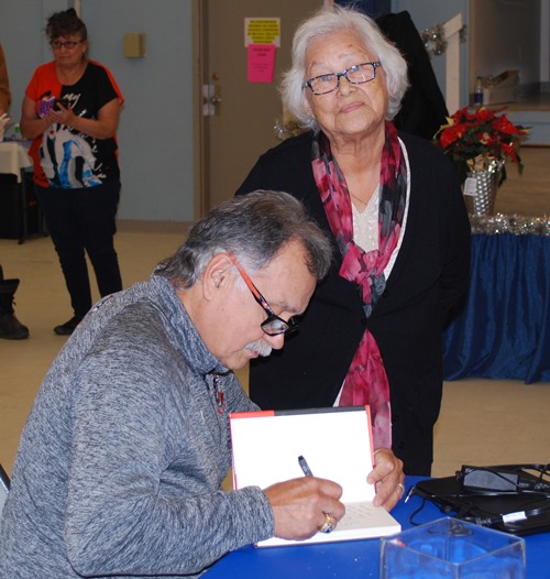 Reggie Leach - the Riverton Rifle - signs a copy of his book for Elder Alvina Bowen after a wonderful day in Conklin Alberta.