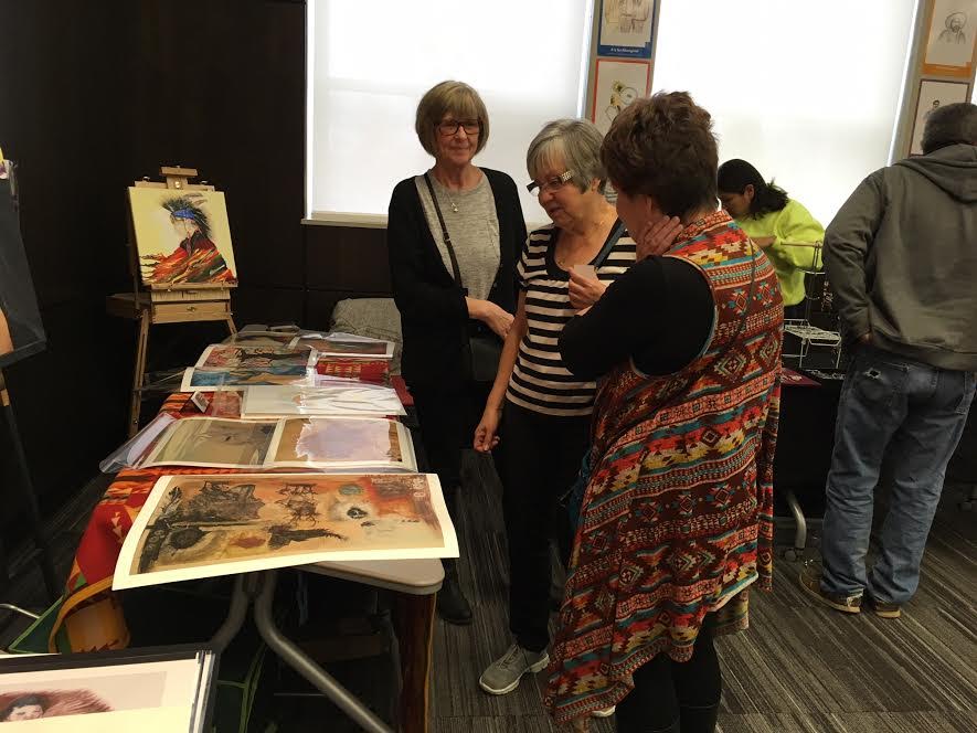 Visitors look over some of the artwork available at the crafts booth. 